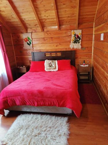 a bedroom with a red bed in a wooden cabin at Cabañas El Diuco en Coñaripe 4 in Coñaripe
