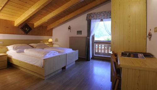 una camera con un grande letto e una finestra di Alpine Touring Hotel-petfriendly a Pozza di Fassa