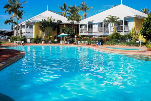 a swimming pool in front of a resort at WhitsunStays - The Resort by the Sea in Mackay