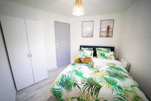 a bedroom with a large bed with a plant printed bedspread at Odelys Premium in Boulogne-sur-Mer