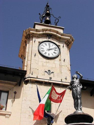 a clock tower with a statue and a flag at Garnì B&B La Rua-Pescocostanzo in Pescocostanzo