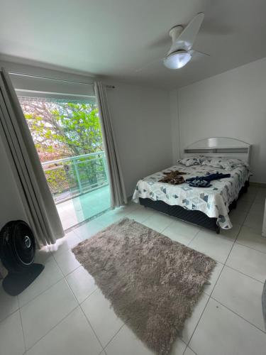 1 dormitorio con cama, ventana y alfombra en Temporada - Cabo Frio, en Cabo Frío