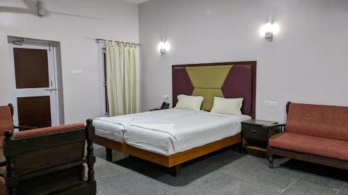 a bedroom with a large bed and two chairs at Kanthi Resorts Badami in Bāgalkot