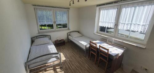 Zimmer mit 2 Betten, einem Tisch und Fenstern in der Unterkunft Apartment Marx in Taltitz