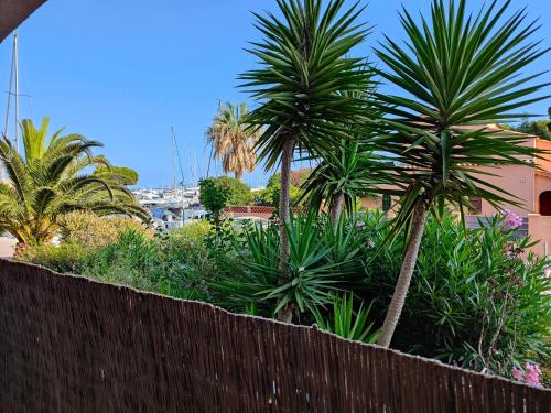 una valla con palmeras frente a un edificio en Suites JM - Le temps d'une Escale (Jacuzzi & Vue Mer) en Hyères