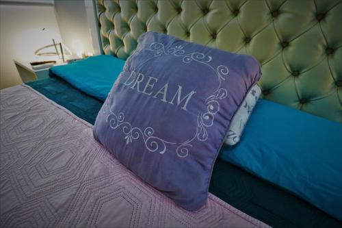 a bed with a purple pillow with dream written on it at Departamento Ibiza in La Paz