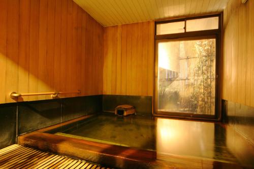 a bath tub in a room with a window at Hotel Danrokan in Kofu