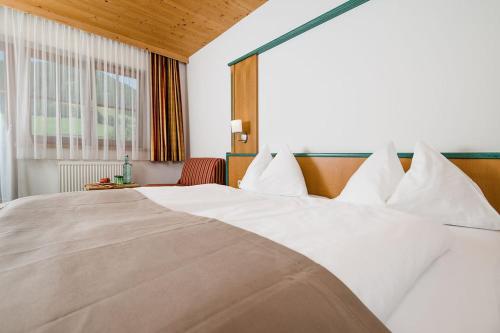 a large bed with white pillows in a hotel room at Hotel Langeck in Maria Alm am Steinernen Meer