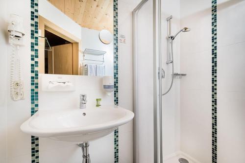 a white bathroom with a sink and a shower at Hotel Langeck in Maria Alm am Steinernen Meer