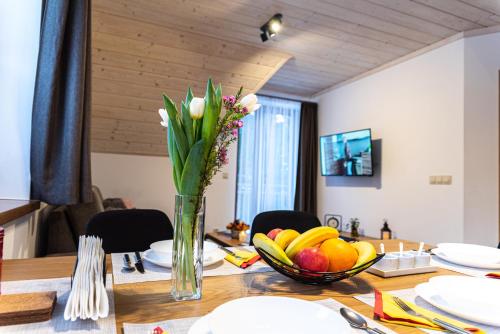 a table with a vase of flowers and fruit on it at MM LUCKY apartments in Demanovska Dolina