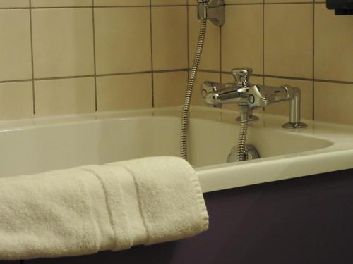 bañera con grifo y toalla en Au Bon Gîte, en Senones