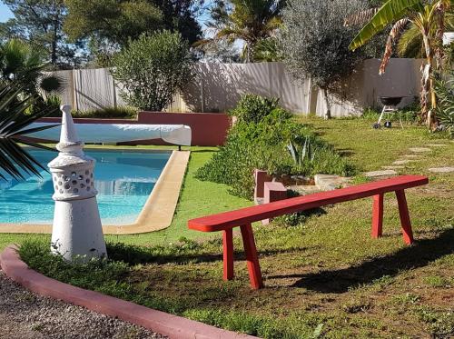 a red bench sitting next to a swimming pool at Bohème Valdareina, Piscine chauffée, Bénagil-Carvoeiro in Carvoeiro