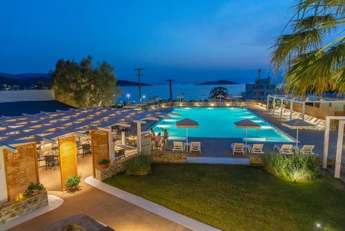 a large swimming pool with chairs and umbrellas at night at Marmari Bay Hotel in Marmarion