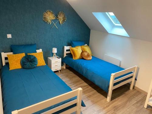 um quarto com 2 camas com almofadas azuis e amarelas em APPARTEMENT CHALEUREUX Wifi et parking gratuit em Givet