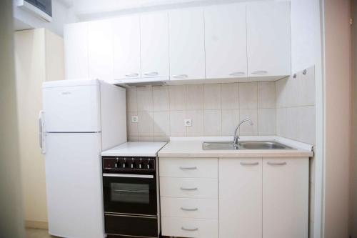 a white kitchen with a sink and a refrigerator at Studio St Stefan in Ohrid
