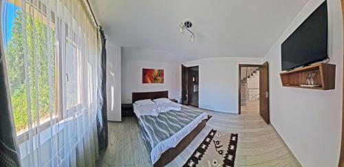 a bedroom with a bed and a large window at Pensiunea Dorul de Munte nr 222 in Rucăr