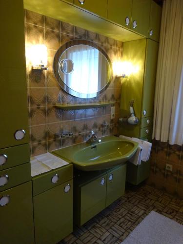 a bathroom with a green sink and a mirror at Haus Grünwald in Gosau