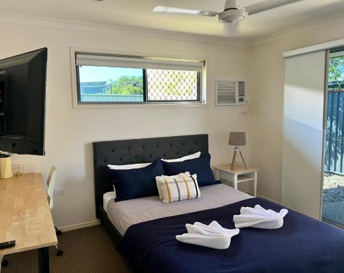 a bedroom with a bed with two white shoes on it at Home away from home - Modern luxury in central Bundaberg in Bundaberg