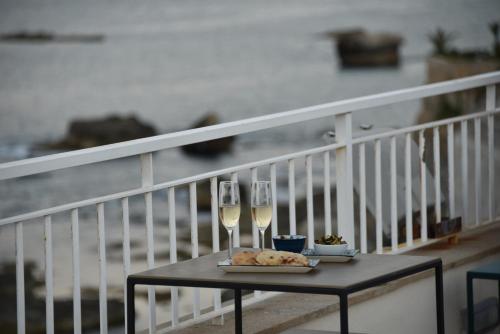 a table with two glasses of wine on a balcony at Giuggiulena in Siracusa