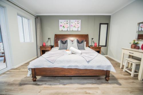a bedroom with a large bed with two pillows at Plettenberg Bay Unit 2 Greenpoint Mews Apartment with Backup Power in Plettenberg Bay