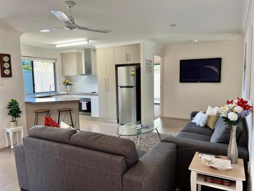 a living room with two couches and a kitchen at Home away from home - Modern luxury in central Bundaberg in Bundaberg