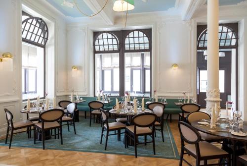 a large room with tables and chairs and windows at Royal St. Georges Hotel Interlaken - MGallery Collection in Interlaken