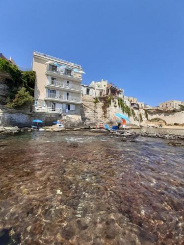 a building on the beach with a body of water at Giuggiulena in Siracusa