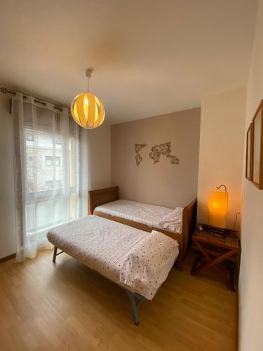 a bedroom with two beds and a table and a lamp at Alojamiento el Dorado in Llanes