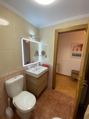 a bathroom with a toilet and a sink and a mirror at Alojamiento el Dorado in Llanes