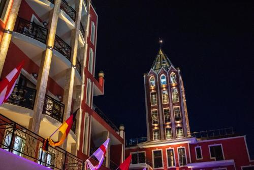 Un palazzo alto con una torre dell'orologio di notte di Alchemist Residence Von Goldenburg a Plovdiv