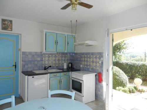 a kitchen with blue cabinets and a ceiling fan at L'Oliveraie in Draguignan