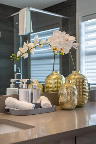 a bathroom counter with gold vases with flowers in it at Contemporary Luxury 4 bedroom House near Downtown in Calgary