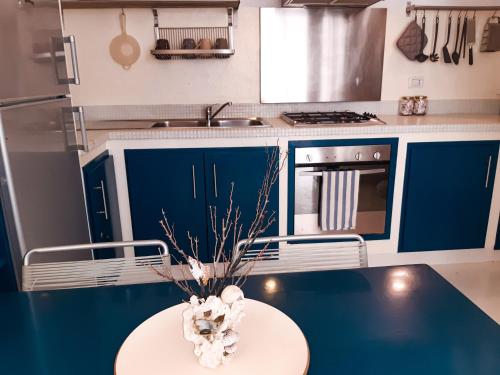 a kitchen with blue cabinets and a table with a vase at App Rosanna, Estoril Beach, 2steps from the sea, Free Wi-Fi & AC in Sal Rei