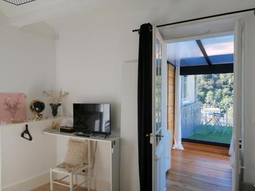 um quarto com uma televisão, uma mesa e uma porta em La Dolce Vita Justine em Vals-les-Bains