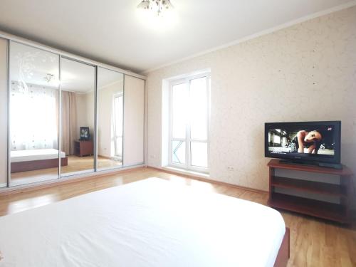a bedroom with a bed and a flat screen tv at Lavina mall apartments 4 in Sumy
