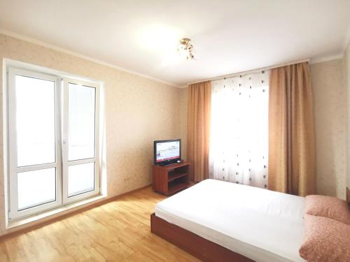 a bedroom with a bed and a tv and a window at Lavina mall apartments 4 in Sumy