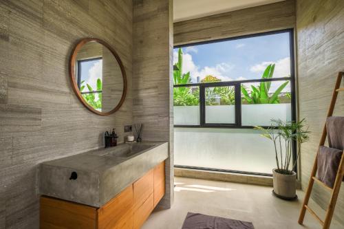 baño con lavabo de hormigón y espejo en Villa Kamal Umalas, en Kerobokan