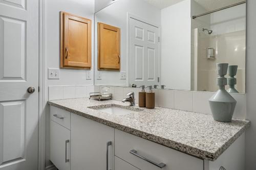 a white bathroom with a sink and a mirror at Modern House with Private Backyard & Fireplace in Calgary