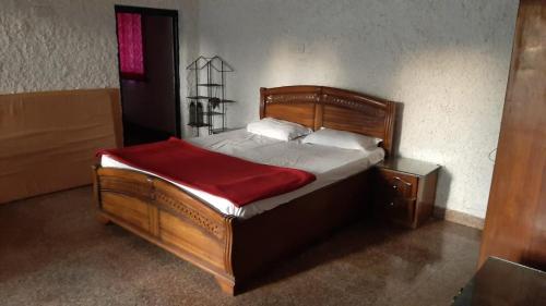 a bedroom with a wooden bed with a red blanket at 2Bhk Villa With Private Swimming Pool Alibaug in Alibaug