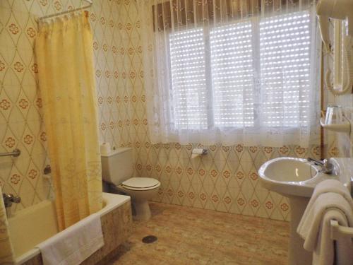 a bathroom with a tub and a toilet and a sink at Hotel Arboleda in A Lanzada