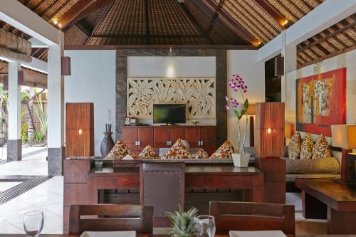a restaurant with a bar with chairs and a television at The Maya Seminyak Villas in Seminyak