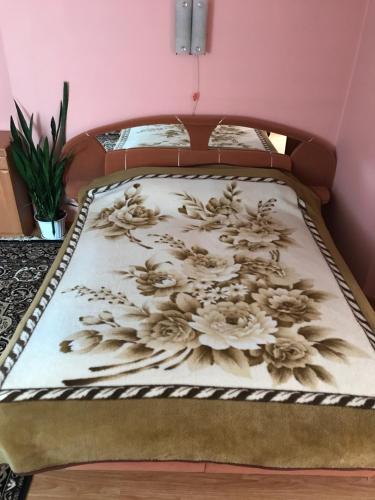 ein Bett mit einer Bettdecke und Blumen darauf in der Unterkunft Апартаменти з окремою ванною кімнатою in Czernowitz
