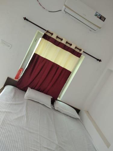 a white bed with a red and yellow blanket at Aashirwad Garden & Resort in Pilani