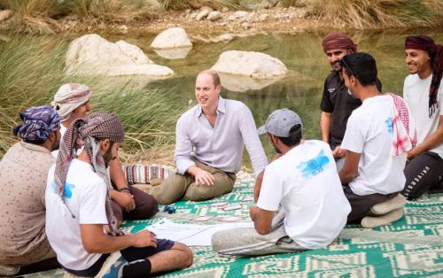 a group of people sitting on the ground near a pond at Wadi Al Arbeieen Resort in Muscat