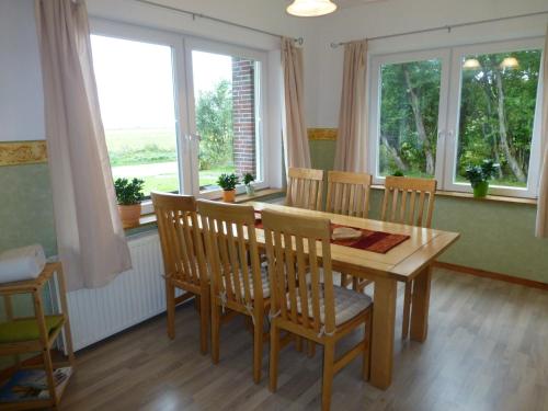 a dining room with a table and chairs and windows at Omas oll Huus in Norden