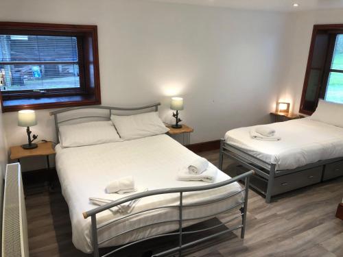 a bedroom with two beds and two windows at Ochiltree cottage in Newton Stewart