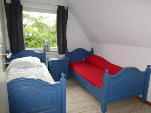 a bedroom with blue and red beds and a window at Omas oll Huus in Norden
