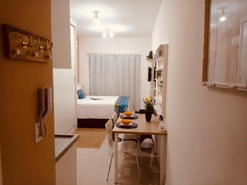 a small kitchen with a table and a room with a bed at Flat Granja Viana - espaço e conforto in Cotia