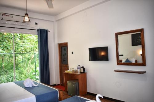 a bedroom with a bed and a mirror and a window at Forest Edge Safari Villa in Udawalawe