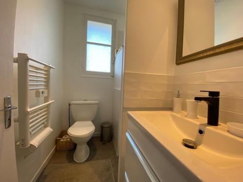 une salle de bain avec un lavabo, des toilettes et un miroir dans l'établissement Chez Banane - Futuroscope - LaConciergerie, à Jaunay-Clan